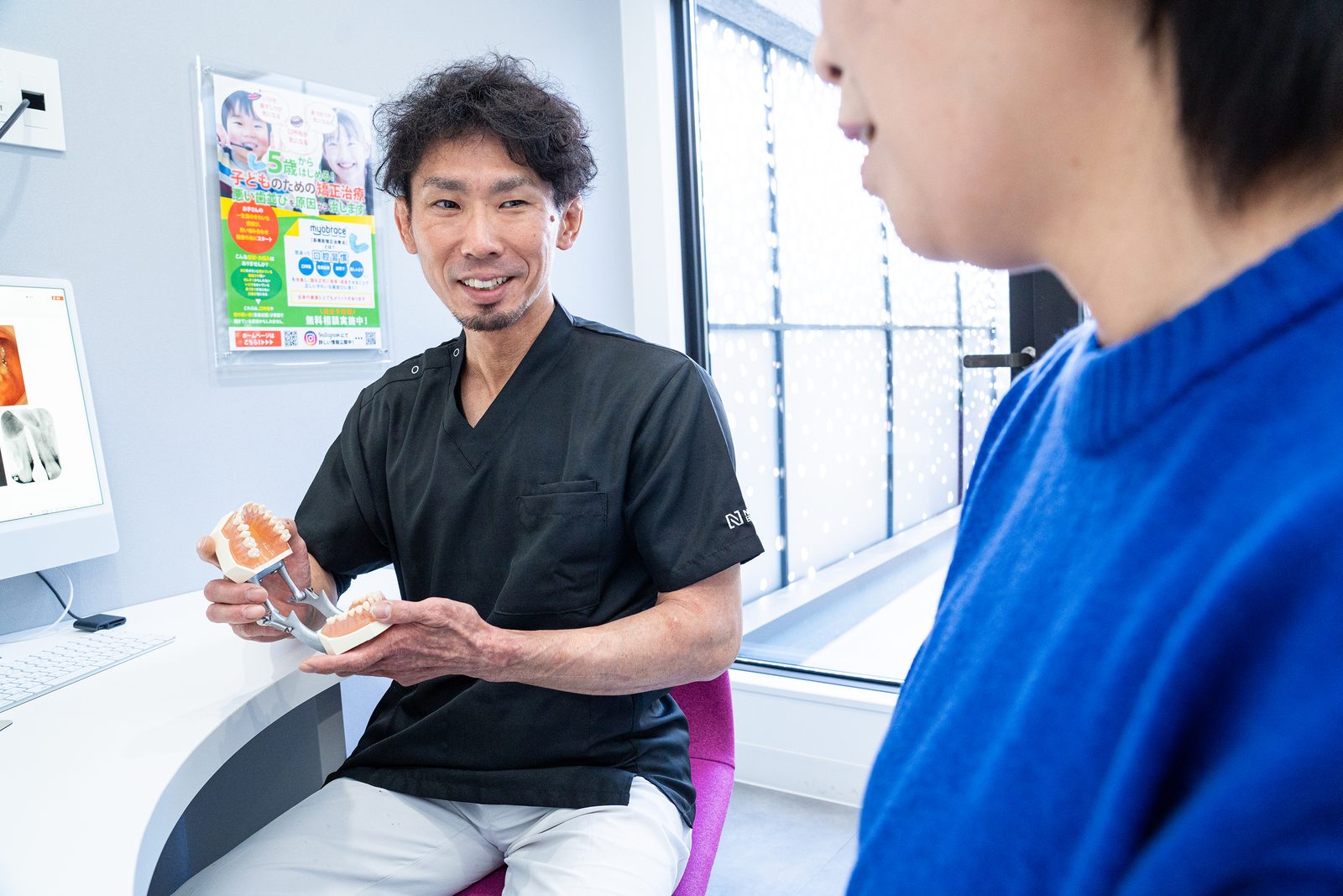 模型を用いてインプラント治療の説明をおこなう歯科医師