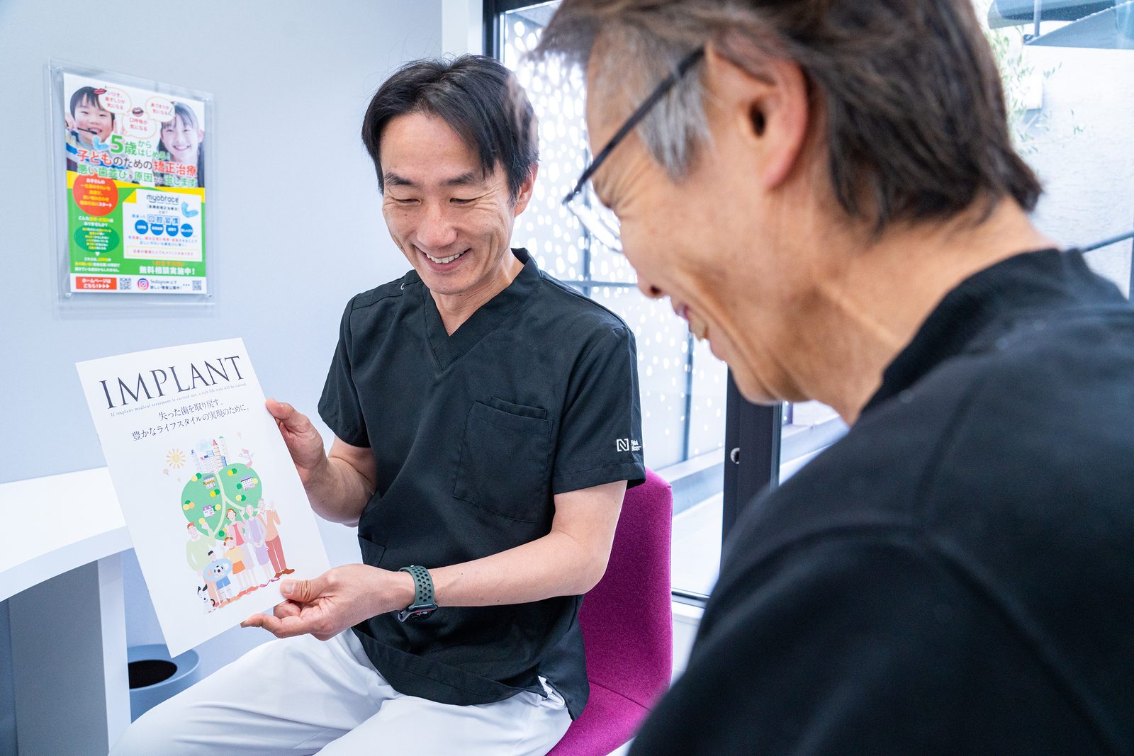 資料を用いて術後の経過について説明する歯科医師